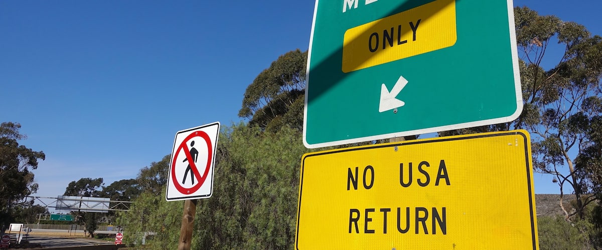 A road sign indicating 'MEXICO ONLY' with a directional arrow and a 'NO USA RETURN' sign below it.