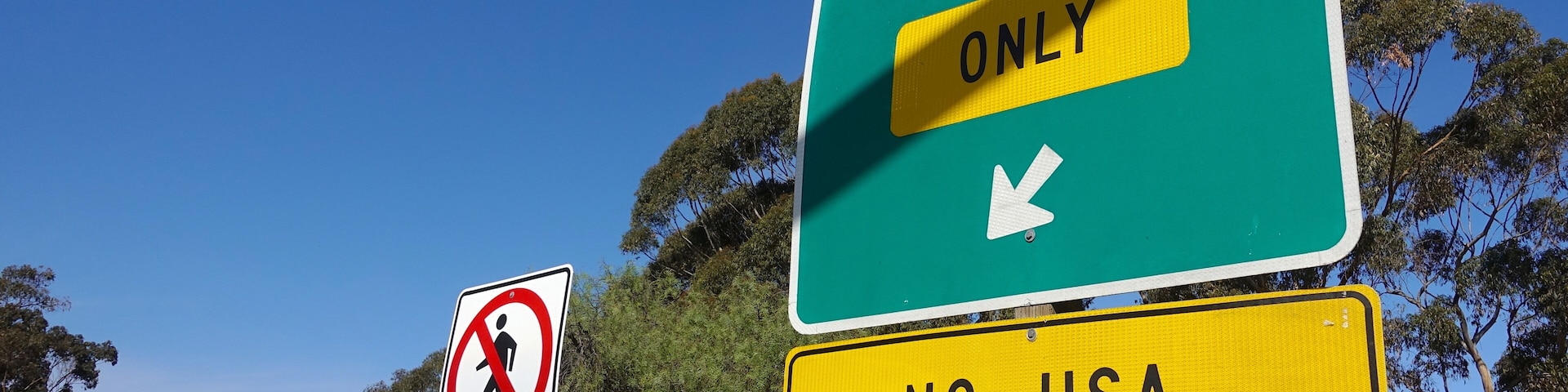 A road sign indicating 'MEXICO ONLY' with a directional arrow and a 'NO USA RETURN' sign below it.