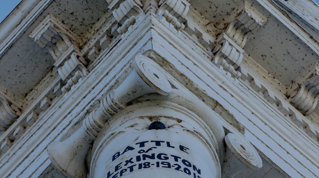 A white column with inscriptions and a clear blue sky with clouds.