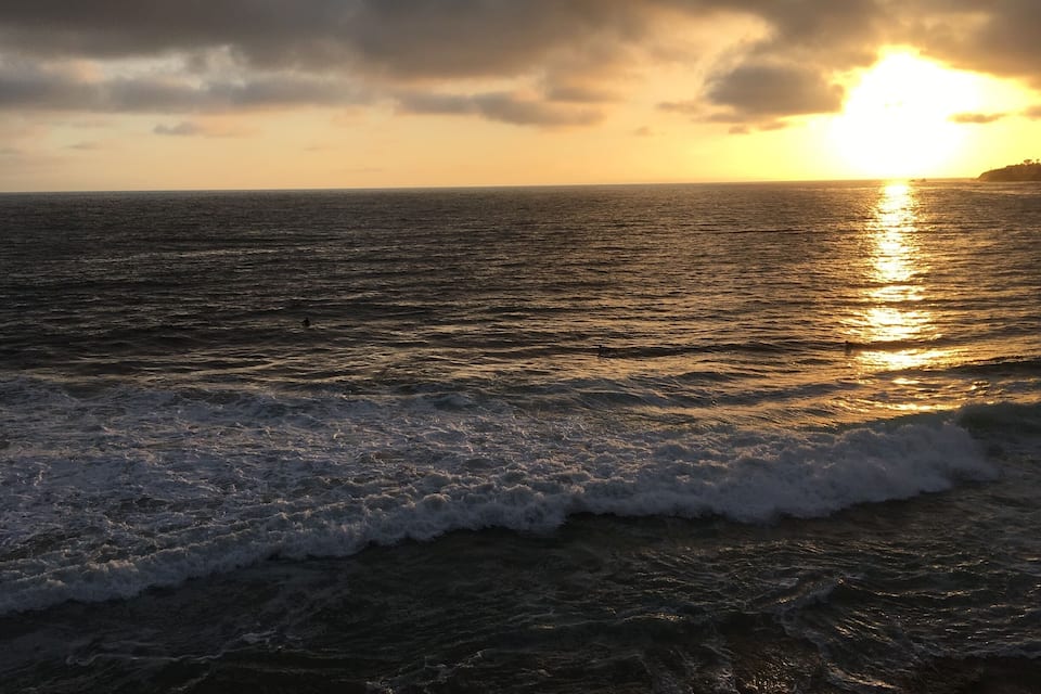 A sunset over the ocean with waves crashing onto the shore.