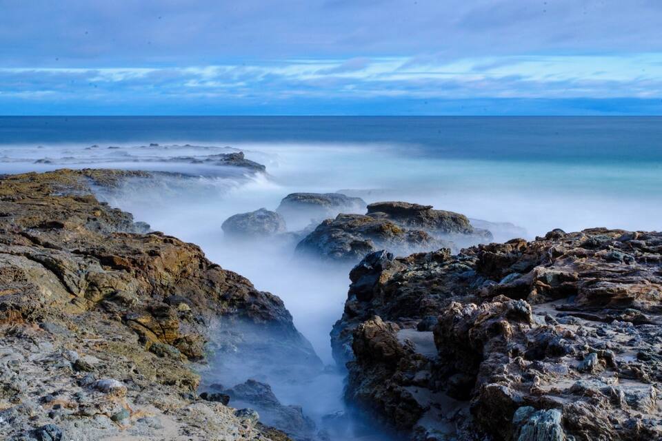A rocky coastline with a misty sea and a clear sky.