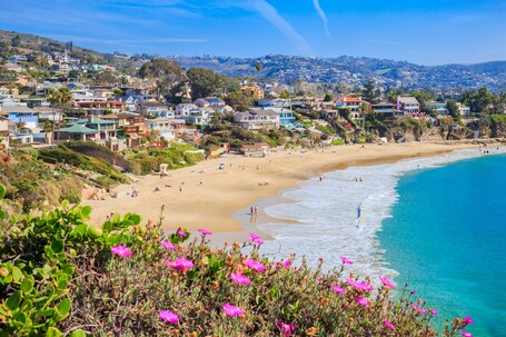 A coastal town with a beach, houses, and a hilly landscape.