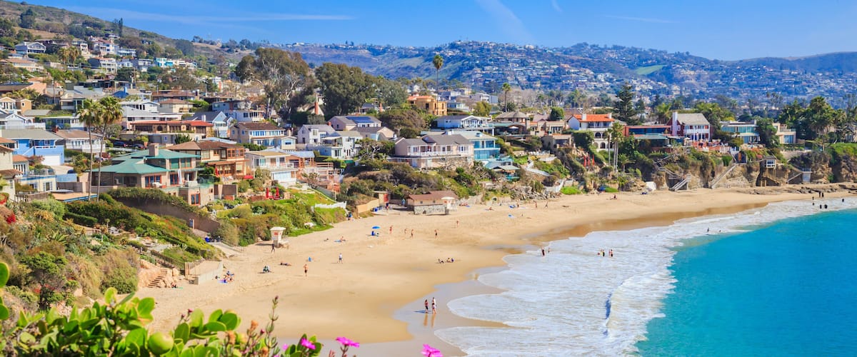 A coastal town with a beach, houses, and a hilly landscape.