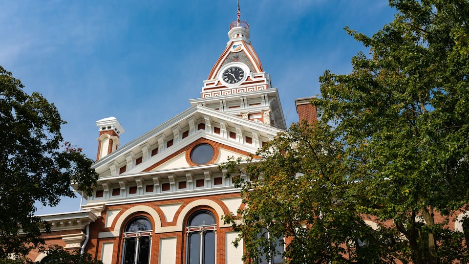A historic building with a clock tower, arched windows, and a prominent chimney.