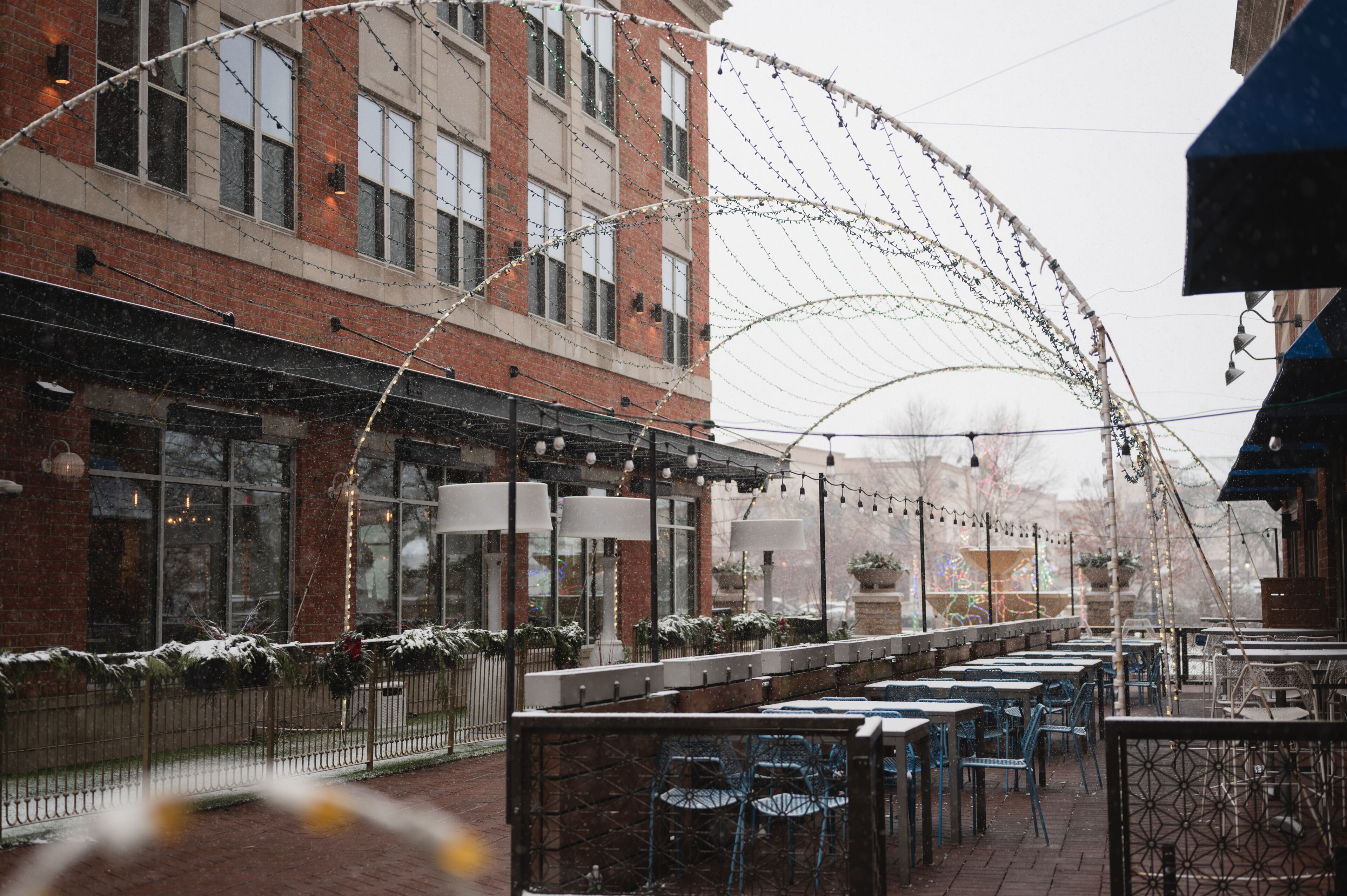 Snowy outdoor dining patio with decorative light arches in downtown Naperville, Illinois