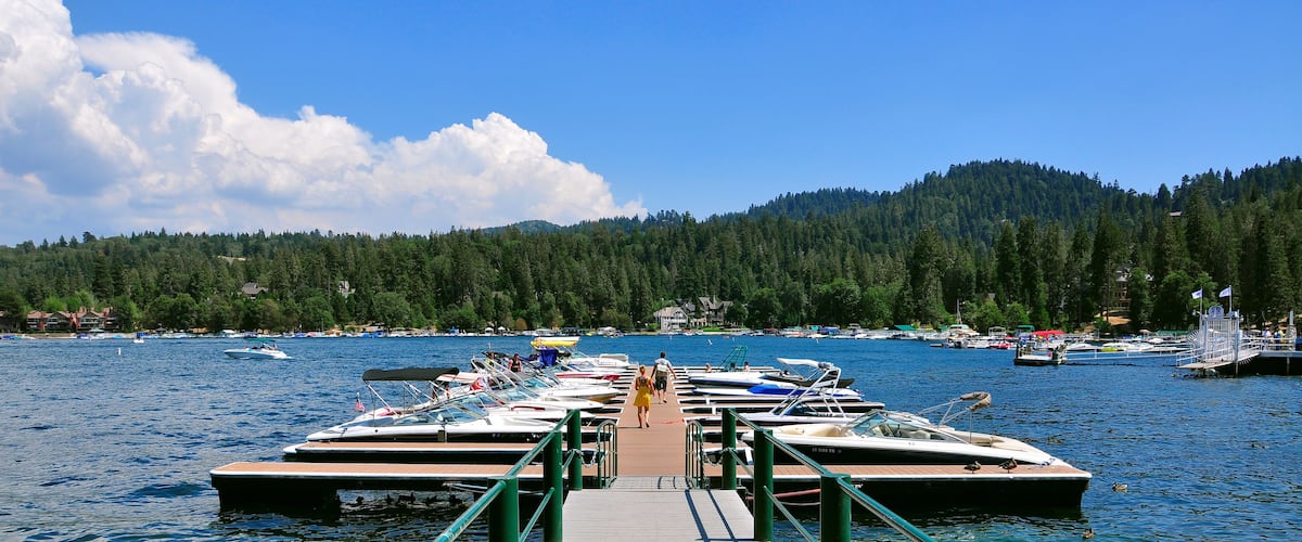 A dock with boats and a forested mountain in the background.