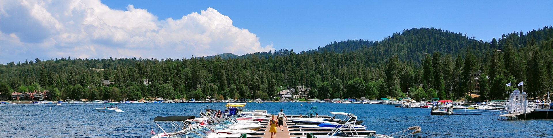 A dock with boats and a forested mountain in the background.