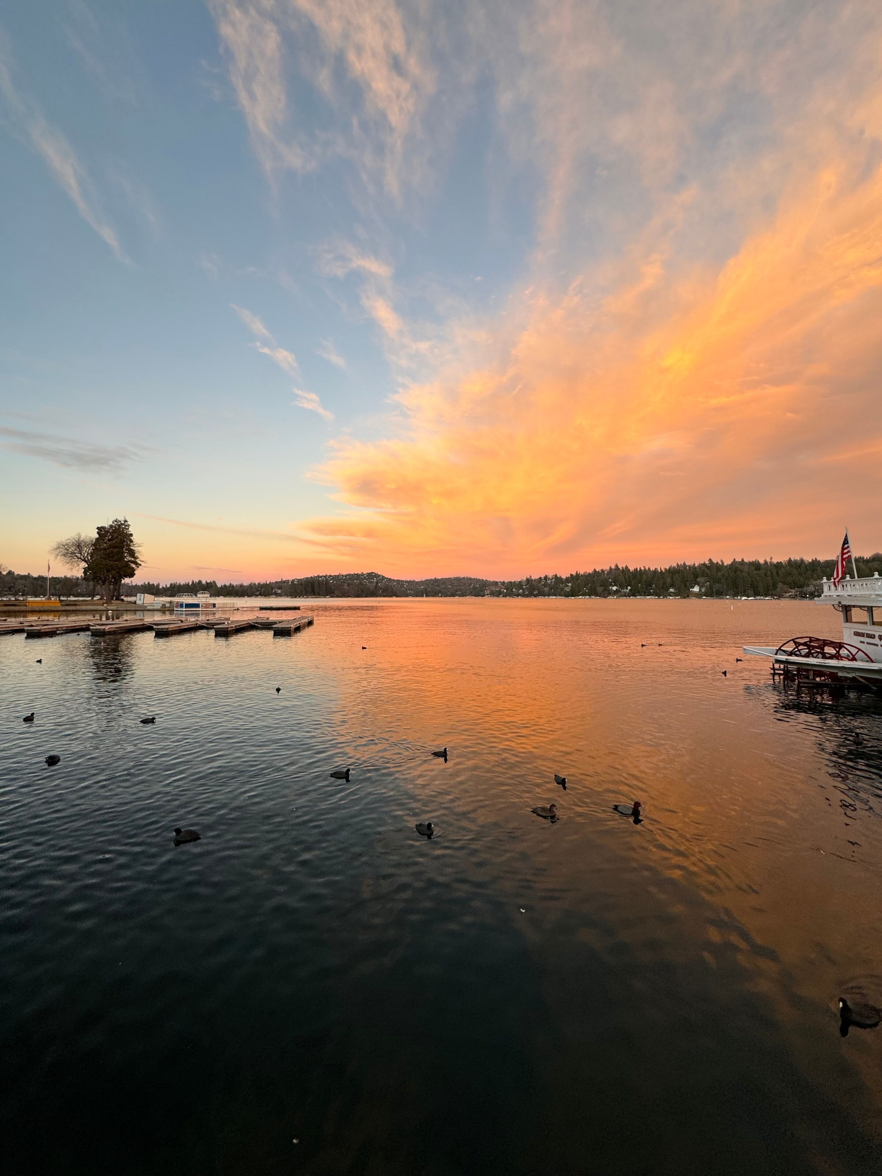 Peaceful lake sunset with golden clouds and ducks on the water