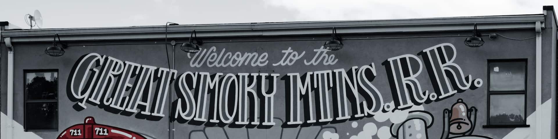 Un mural de un tren rojo con el texto 'Welcome to the Great Smoky Mountains, N.R.'