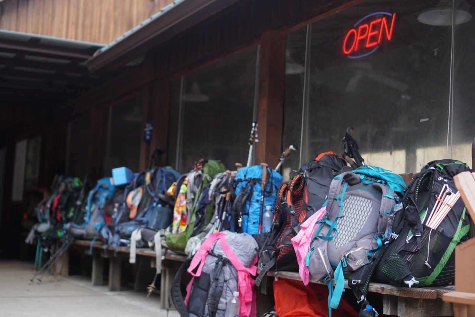 A row of backpacks outside a building with an 'OPEN' sign.