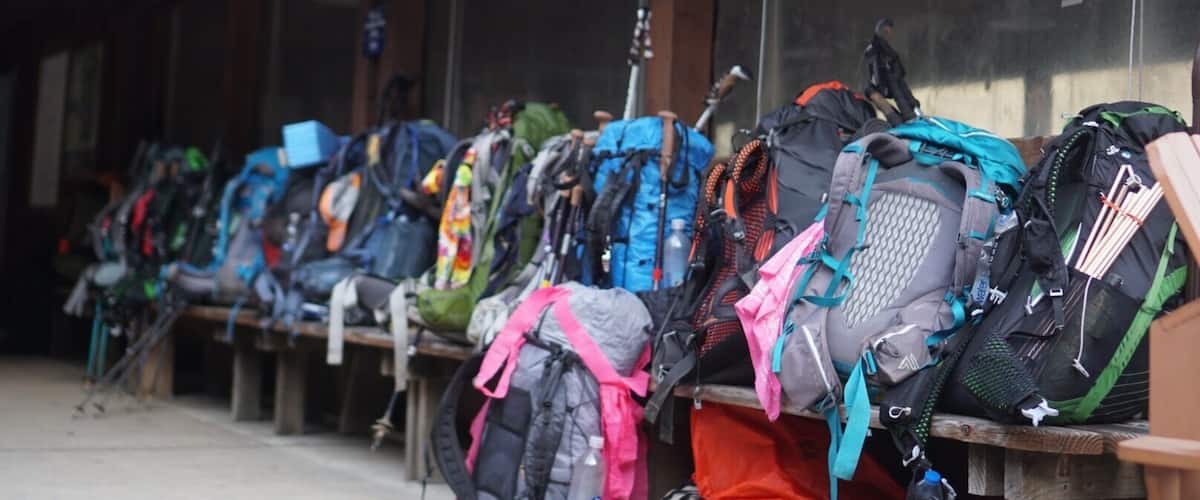 A row of backpacks outside a building with an 'OPEN' sign.
