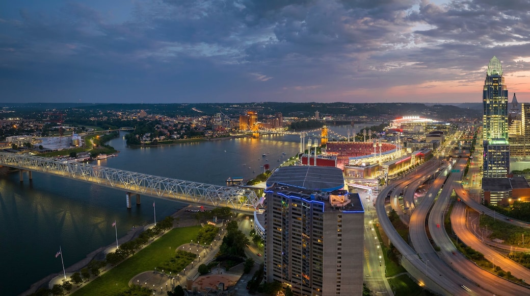 A cityscape with a river, a bridge, and a stadium at dusk.