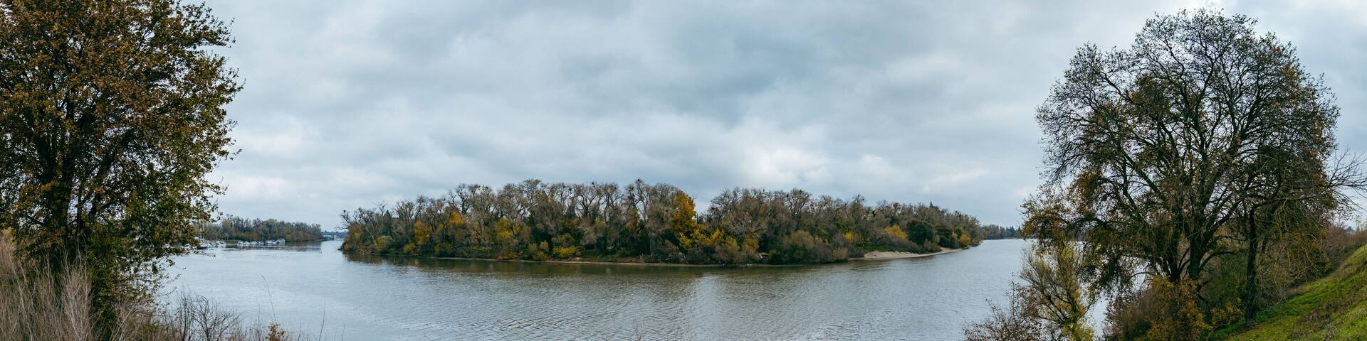 panorama captures the serene Sacramento River winding past banks lined with autumn trees