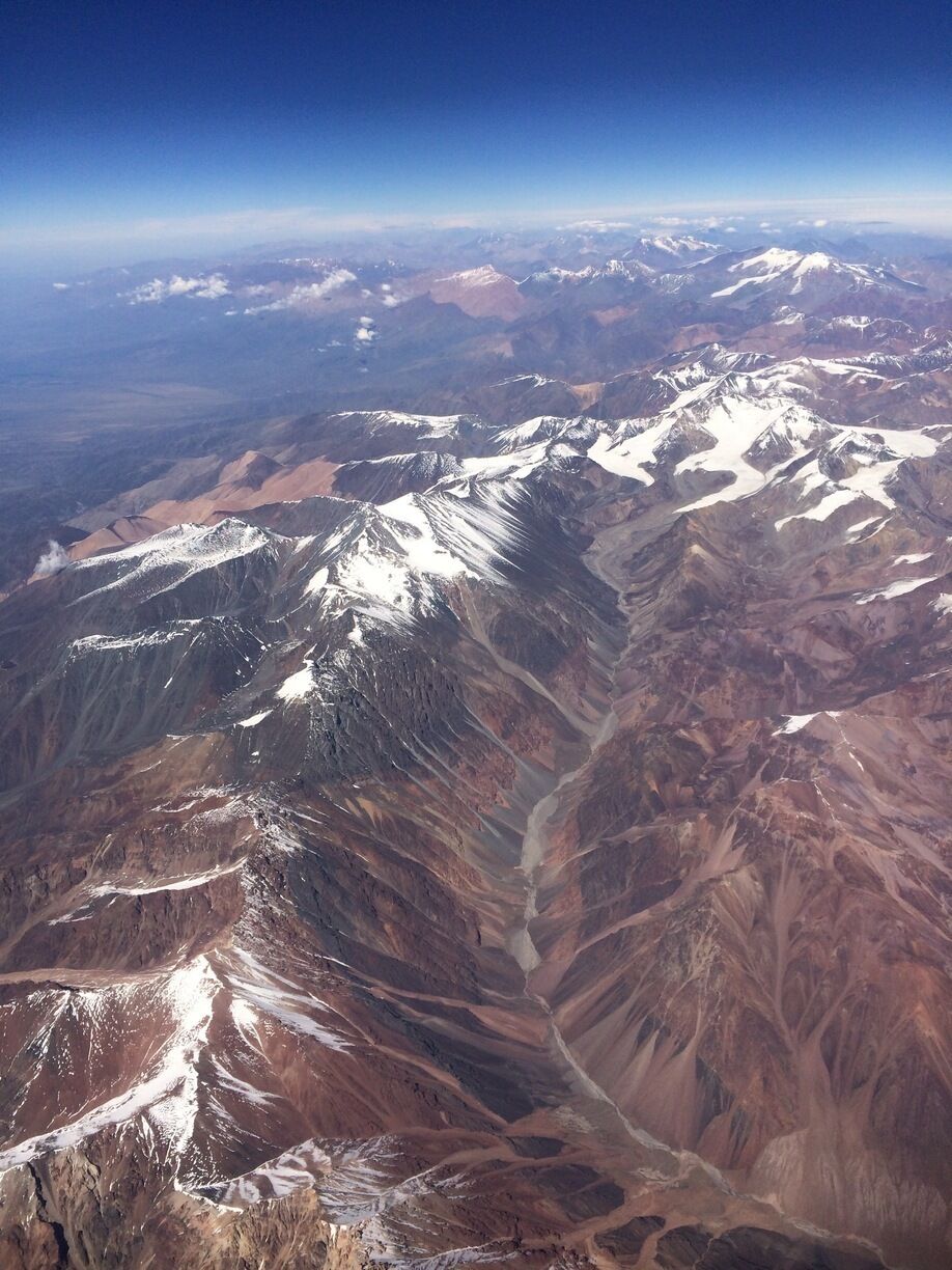 A vast mountain range with snow-capped peaks and deep valleys.