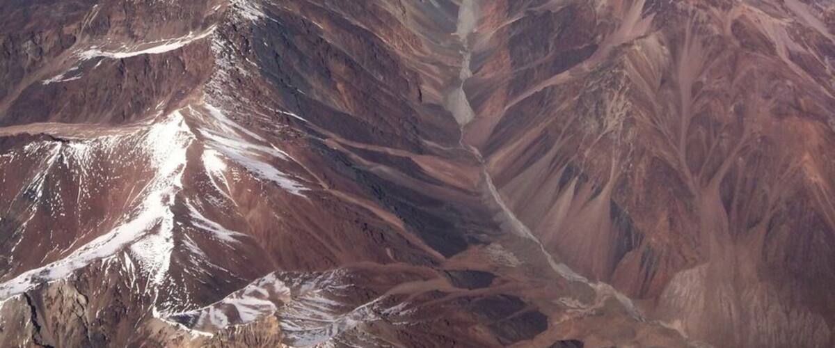 A vast mountain range with snow-capped peaks and deep valleys.