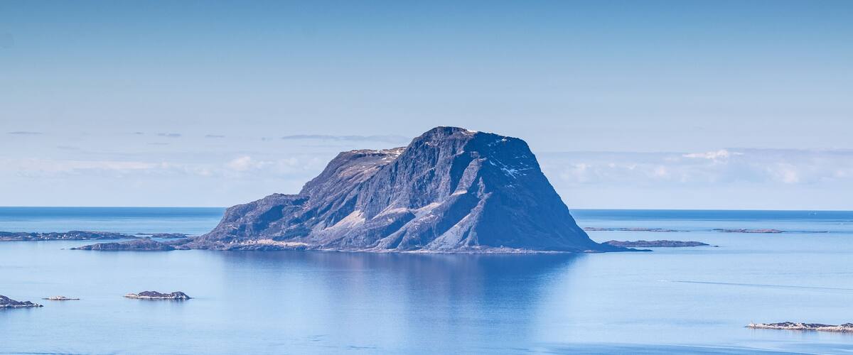 A solitary mountain peak surrounded by calm waters.