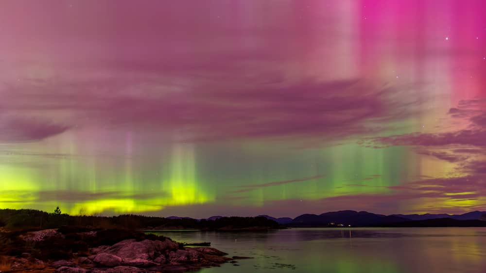 Multicoloured northern light with reflections on land and sea