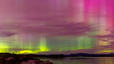 Multicoloured northern light with reflections on land and sea