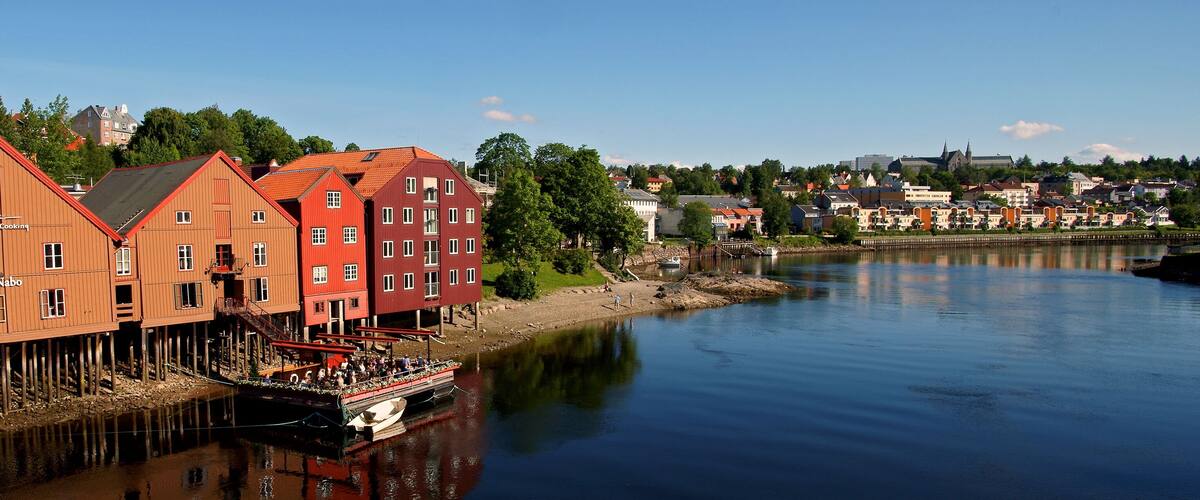 A river with wooden buildings and a boat docked at the shore.