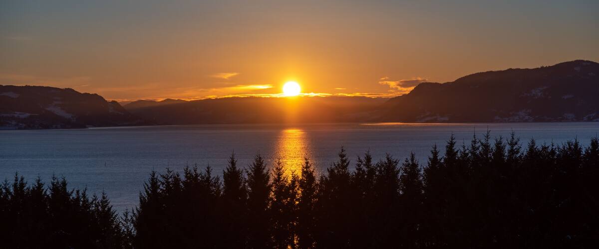 A sunset over a calm lake with mountains in the background.