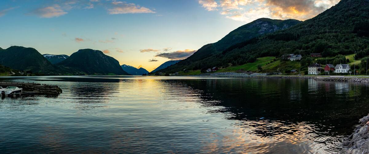 A calm lake with boats, surrounded by mountains and houses.