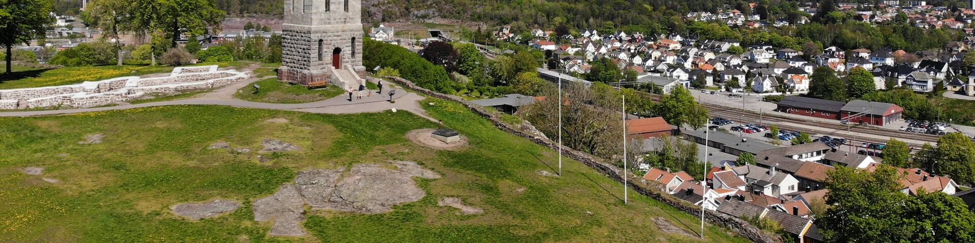 Created by dji drone camera of Slottsfjell an architecture building from medieval times in the oldest city of Norway with a village in the background and the Norwegian flag on top in the summer