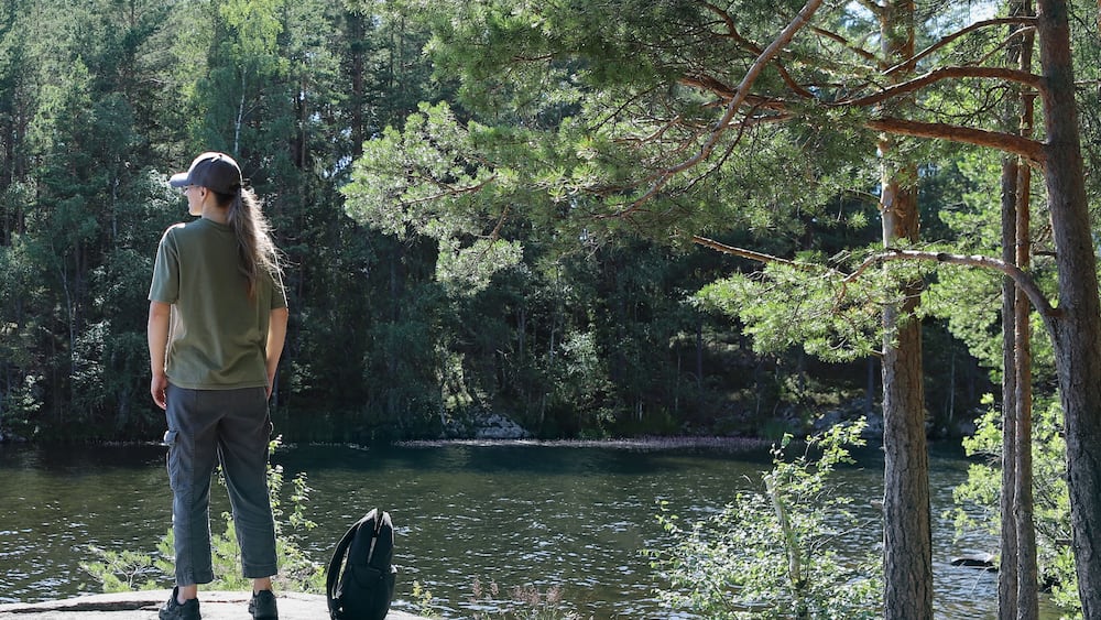 Woman enjoying the view by the lake. Woman hiking in forest near lake in Norway, Oslo, Østensjøvannet lake.