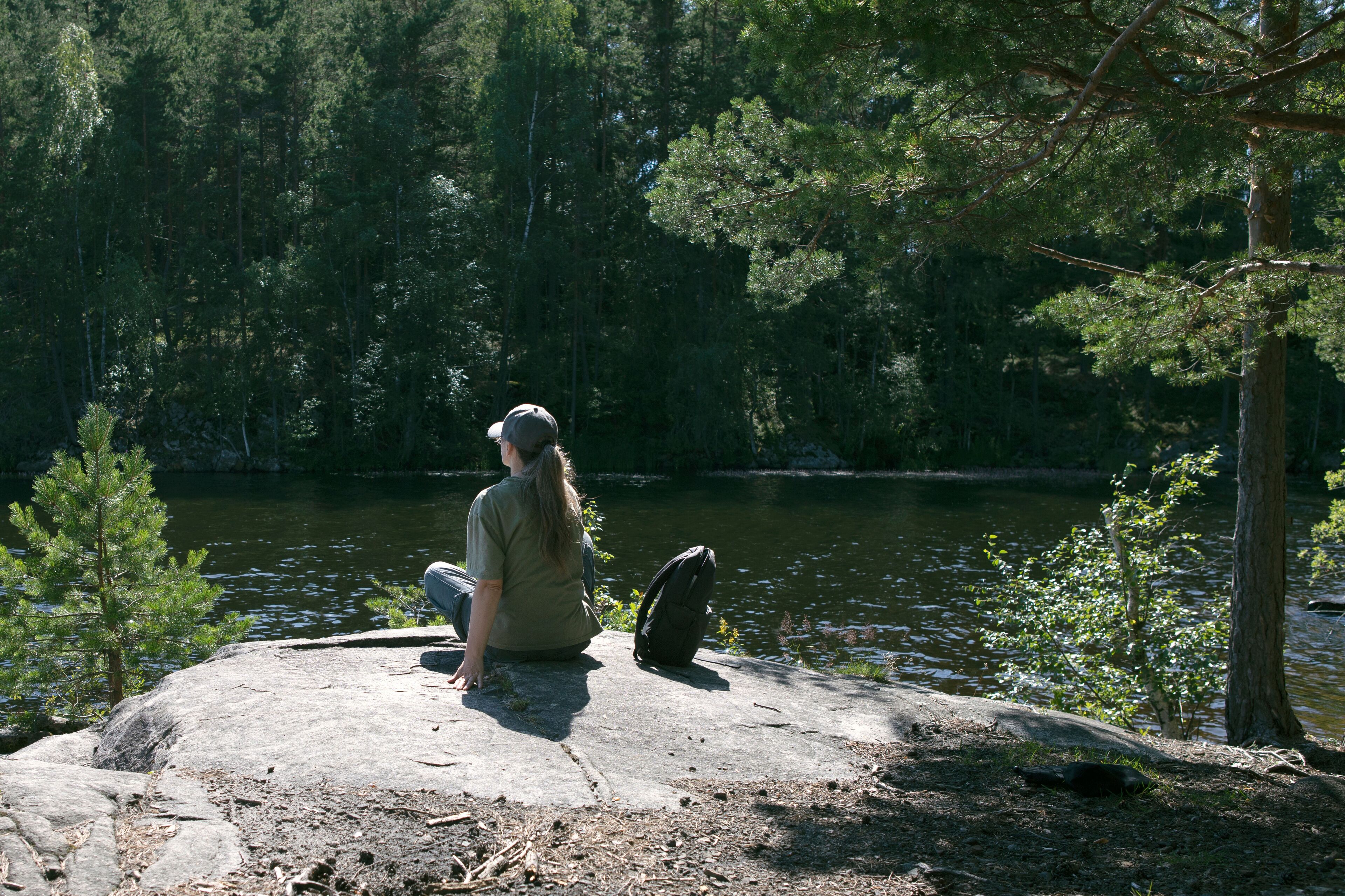 Woman enjoying the view by the lake. Woman hiking in forest near lake in Norway, Oslo, Østensjøvannet lake.