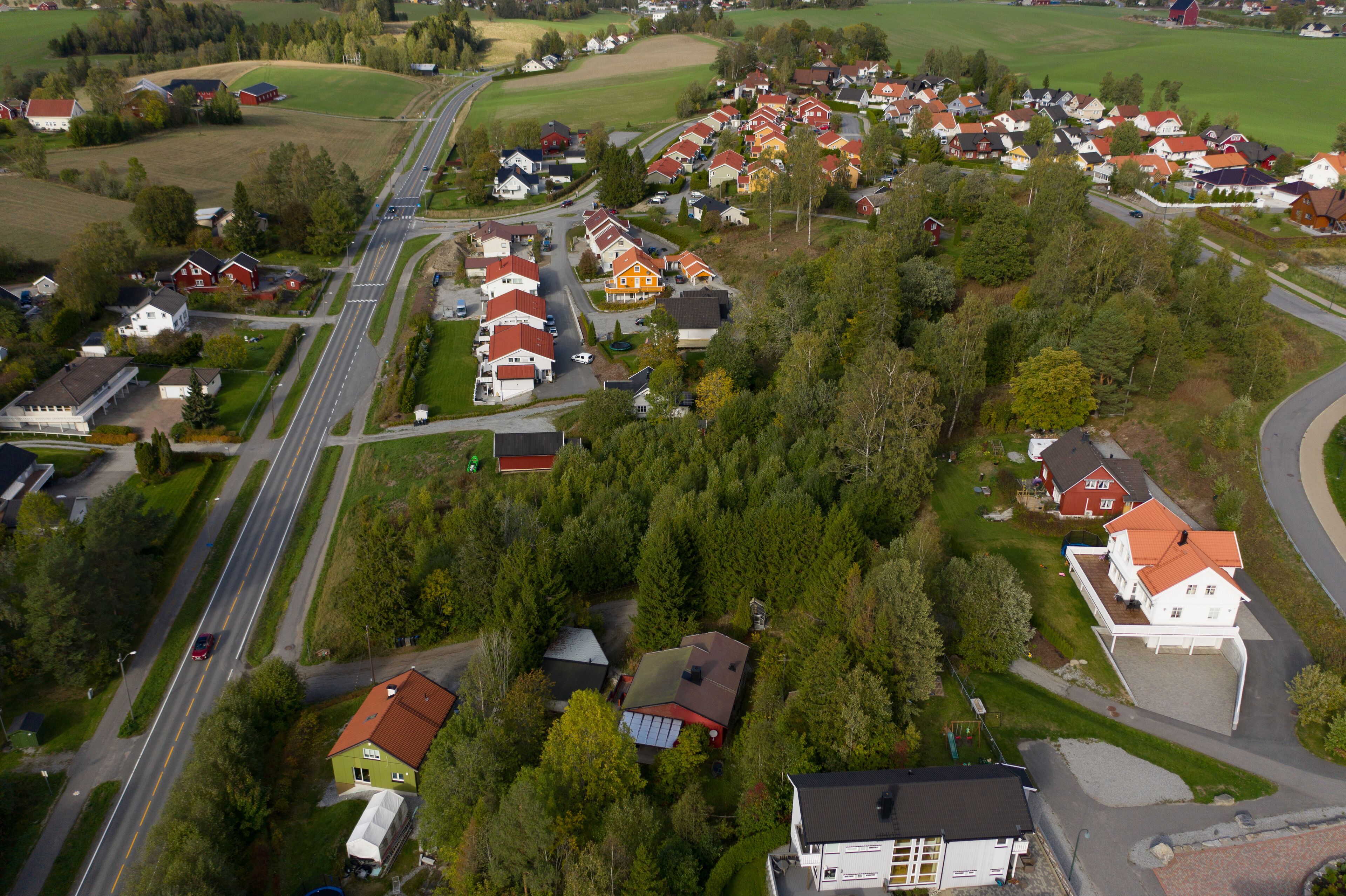 An aerial view of a residential area with houses, roads, and surrounding greenery.