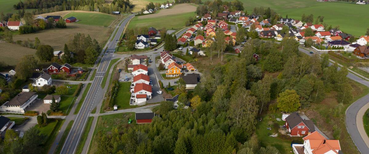 An aerial view of a residential area with houses, roads, and surrounding greenery.