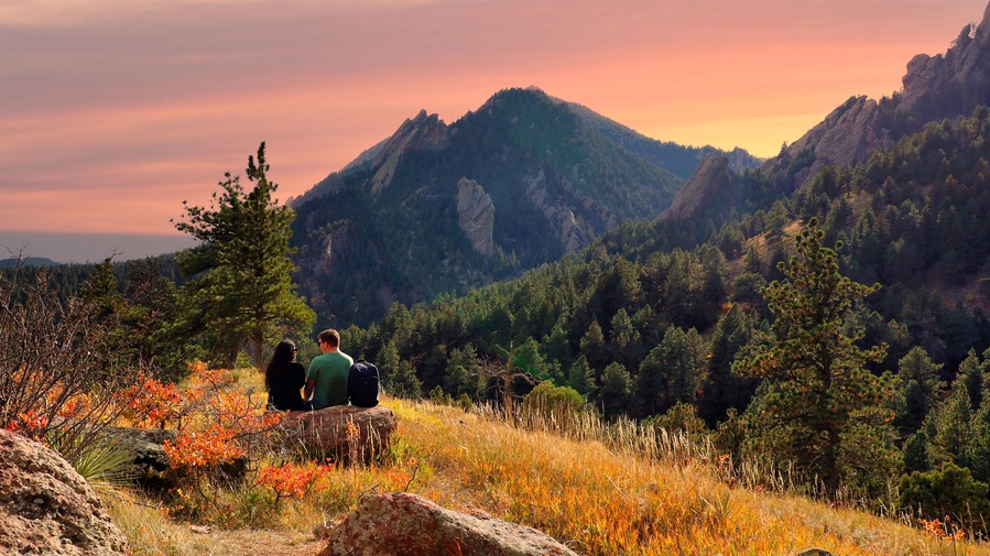 Hiking couple taking a break along Boulder, Colorado's Mesa Trail at dusk