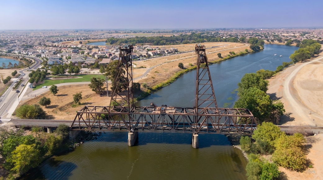 Aerial view of the Mossdale Railroad Bridge, a historic vertical-lift bridge, spanning the San Joaquin River in Lathrop, California, USA, Residential areas in the background.