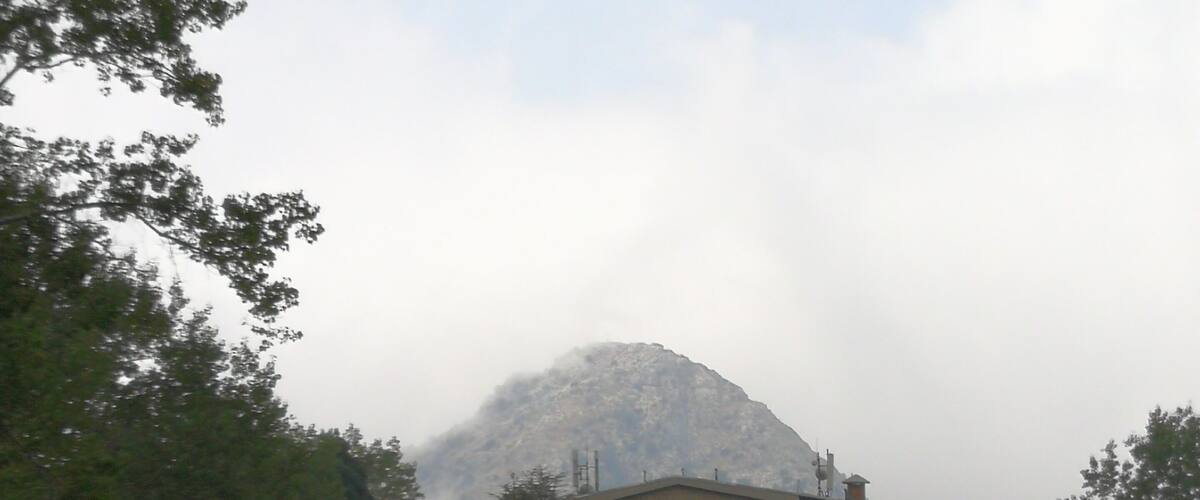 A building surrounded by trees and a mountain in the background.