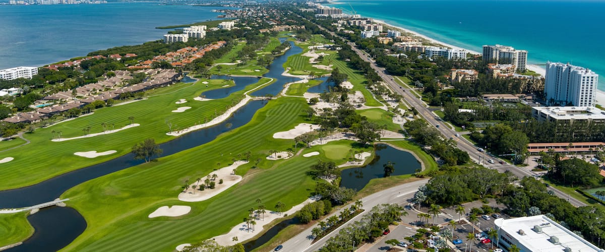 Un paysage urbain côtier comprenant un terrain de golf, des zones résidentielles et un port de plaisance.