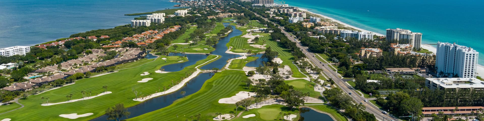 A coastal cityscape with a golf course, residential areas, and a marina.