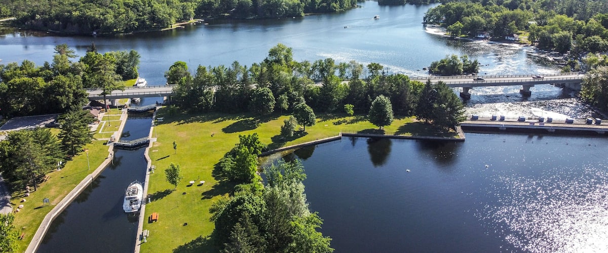 A river with a bridge, boats, and a grassy area with trees.