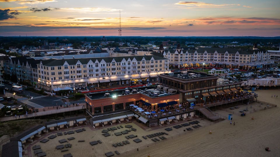 A coastal resort with a large hotel, beach area, and a boardwalk.