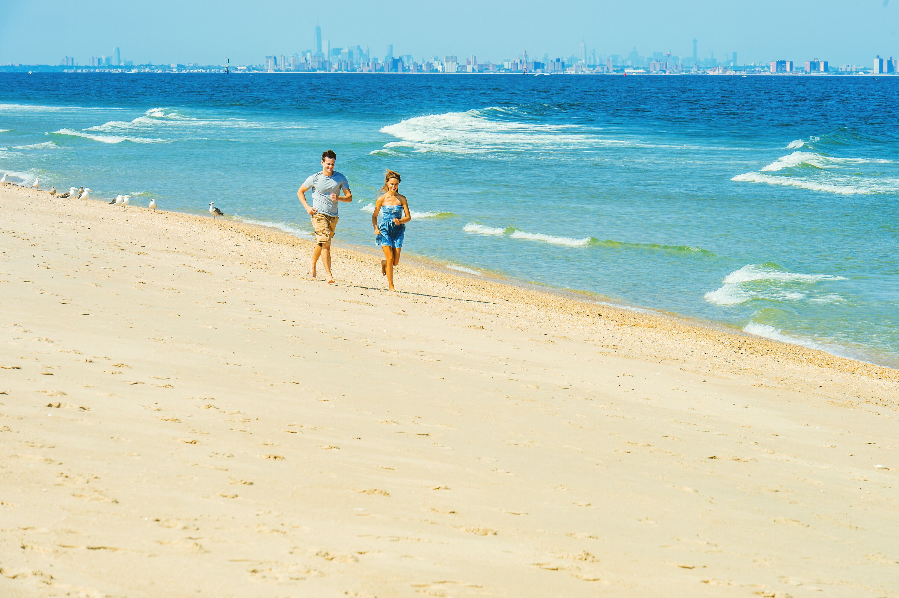 Young couple running on Sandy Hook Beach, New Jersey, USA.