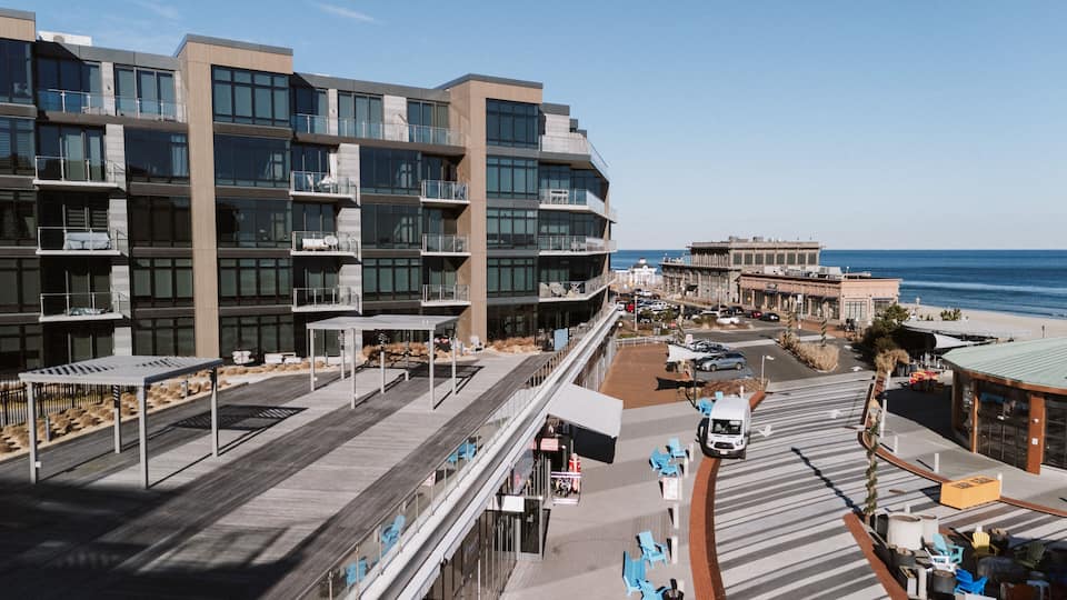 A coastal urban area with modern buildings, a boardwalk, and a view of the ocean.