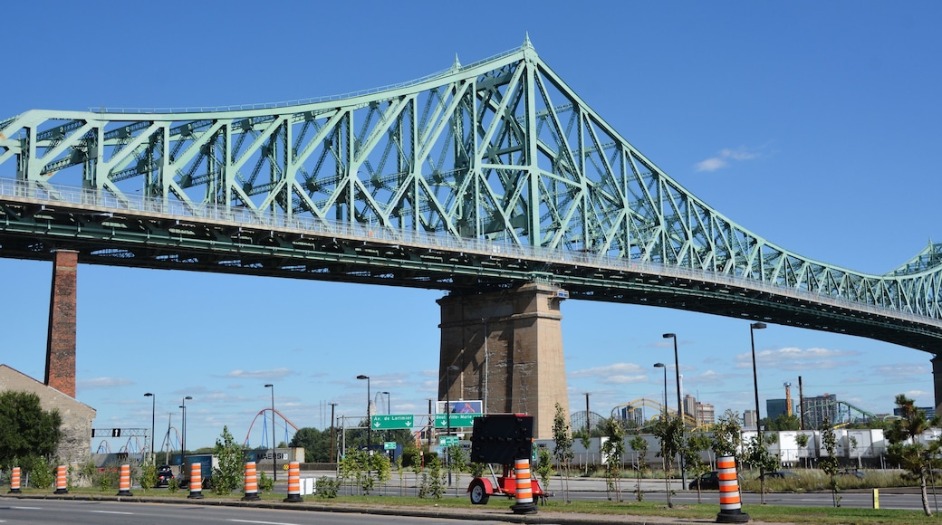 A large green bridge with multiple lanes, traffic cones, and street signs.