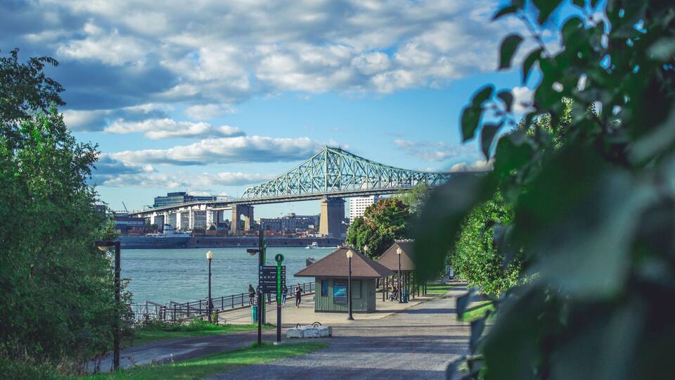 A river with a bridge, a gazebo, and a park with trees.