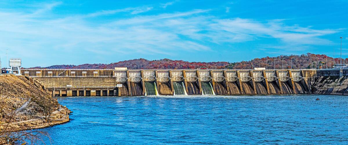 A dam with multiple gates releasing water into a river.