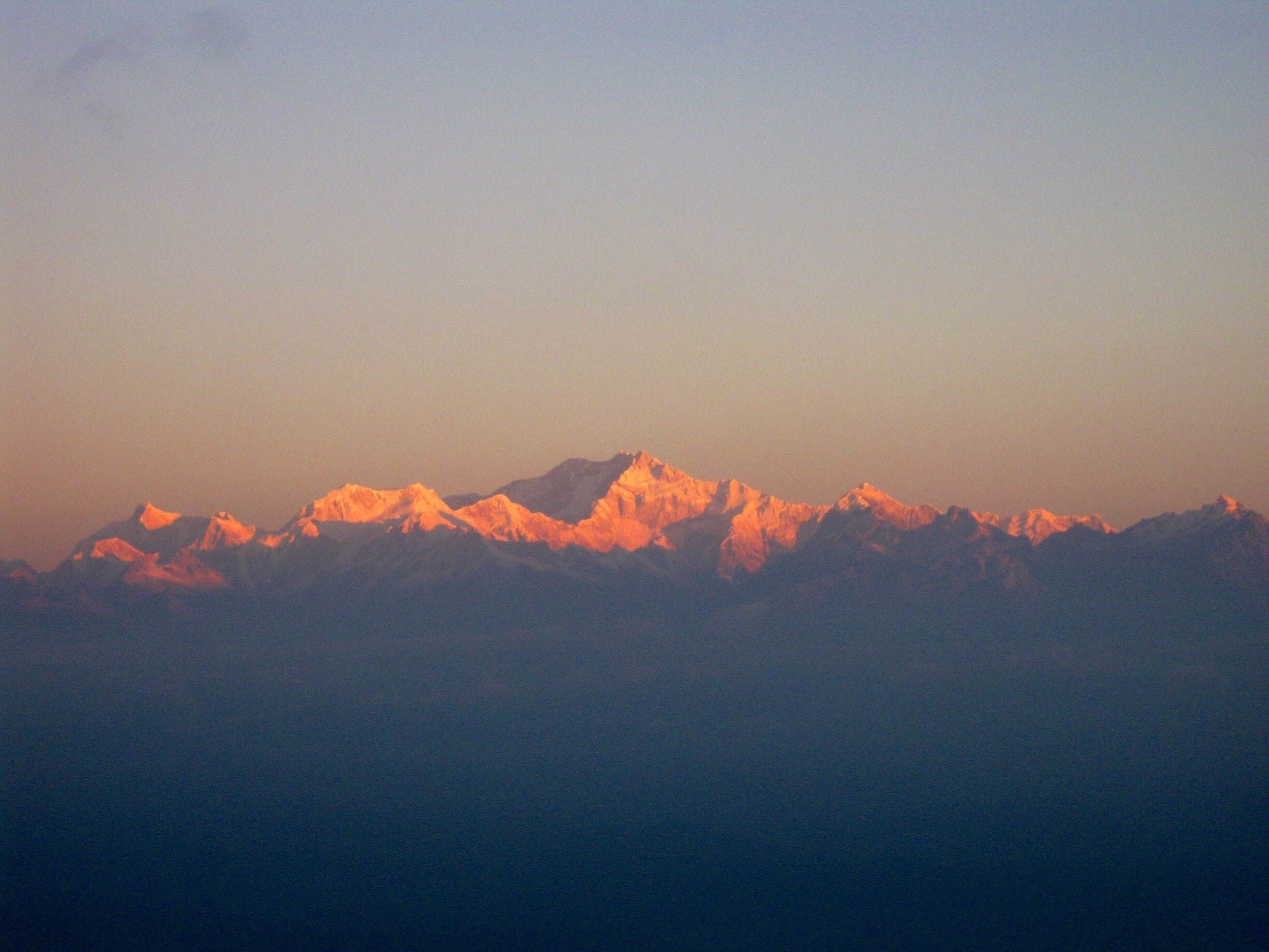 A mountain range with snow-capped peaks during sunset.