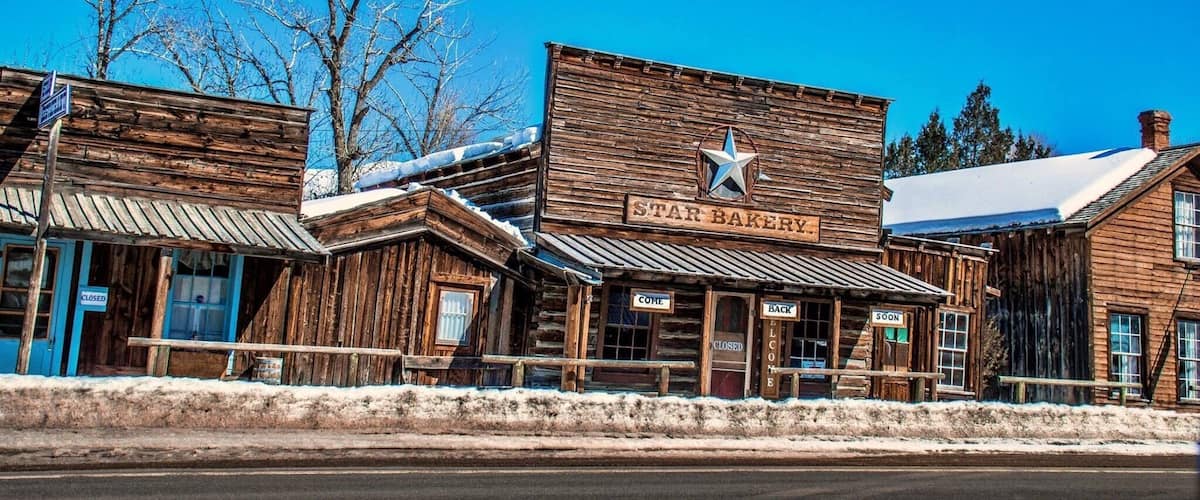 A rustic wooden building labeled "STAR BAKERY" with a star emblem, surrounded by snow-covered trees and a clear blue sky.