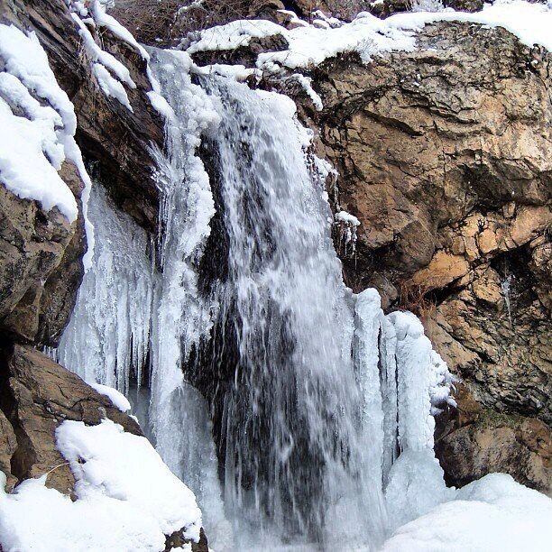 A waterfall cascading over rocky terrain with snow accumulation.