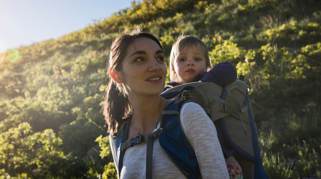Mother carrying young daughter on back, hiking the Bonneville Shoreline Trail in the Wasatch Foothills above Salt Lake City, Utah, USA