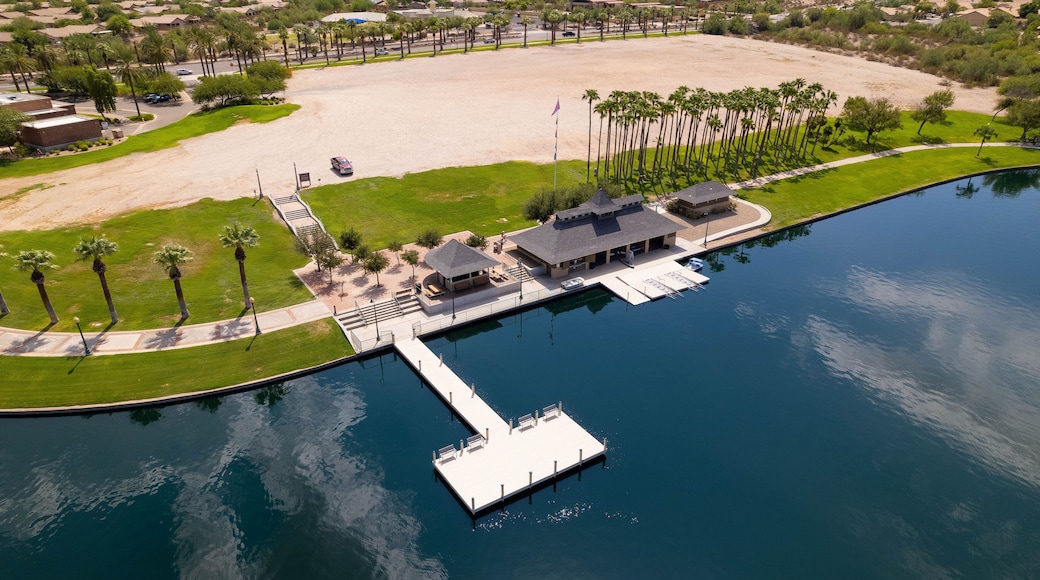 A marina with a dock extending into a calm body of water, surrounded by a landscaped area with palm trees and a sandy beach.