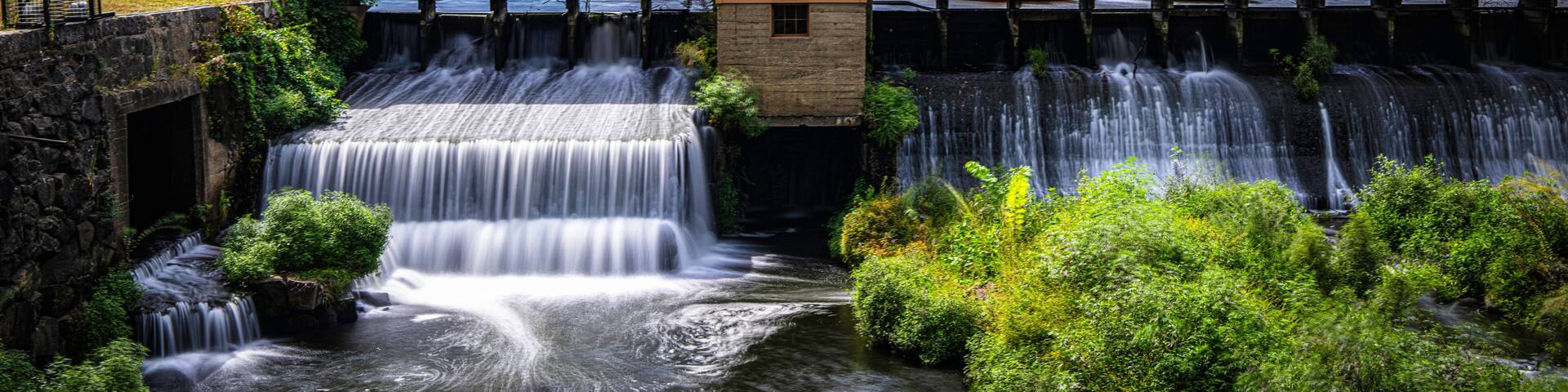 Autumn landscape after a rainstorm in Lowell, Massachusetts. Blue clouds drift above the Lower Locks Gatehouse and Merrimack River, a Historic Civil Engineering Landmark within the National Park.