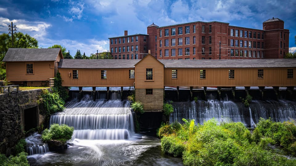 Autumn landscape after a rainstorm in Lowell, Massachusetts. Blue clouds drift above the Lower Locks Gatehouse and Merrimack River, a Historic Civil Engineering Landmark within the National Park.