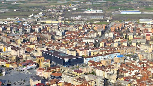 Uma área urbana densamente construída, com um edifício moderno proeminente identificado com a placa 'GLOBAL', e uma combinação de edifícios residenciais e comerciais.